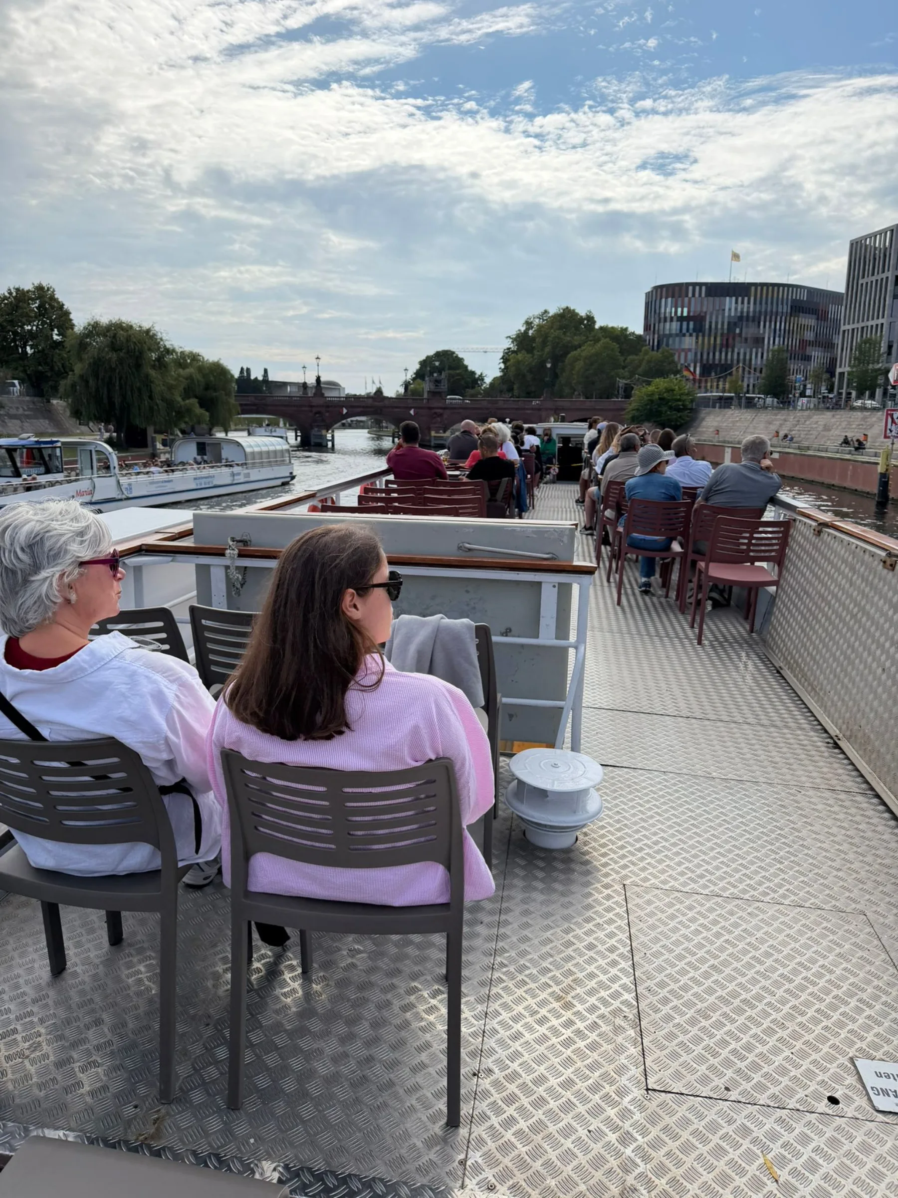 Fahrgäste sitzen an Tischen auf dem Außendeck