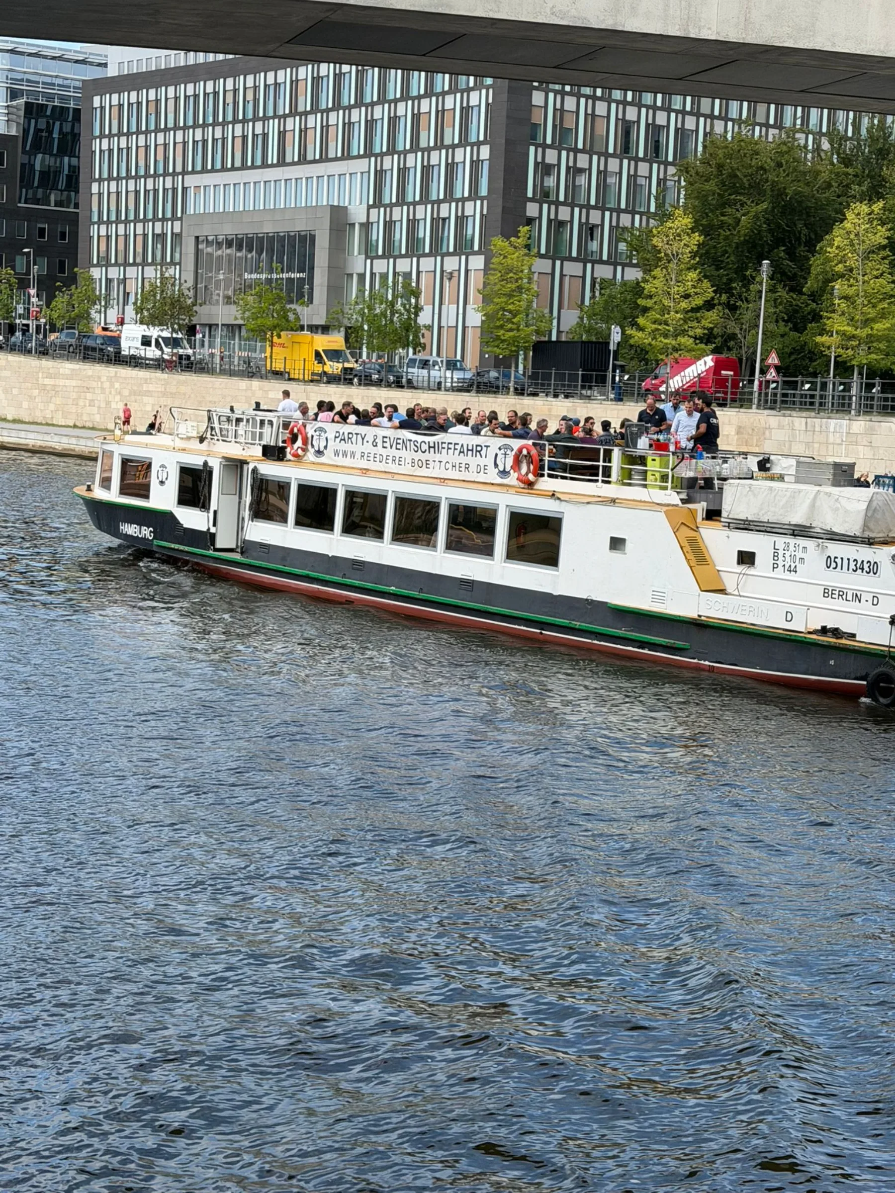 Fahrgastschiff vor einem großen Gebäude am Ufer
